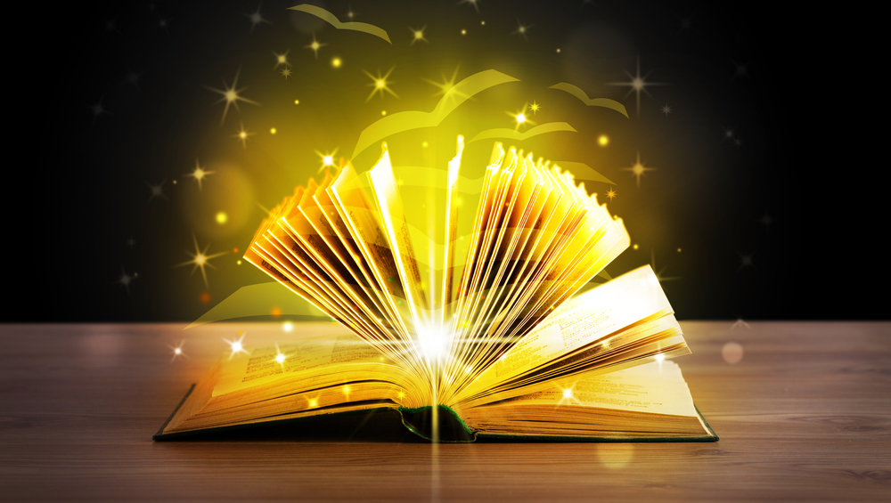 Open book with golden glow flying paper pages on wooden deck